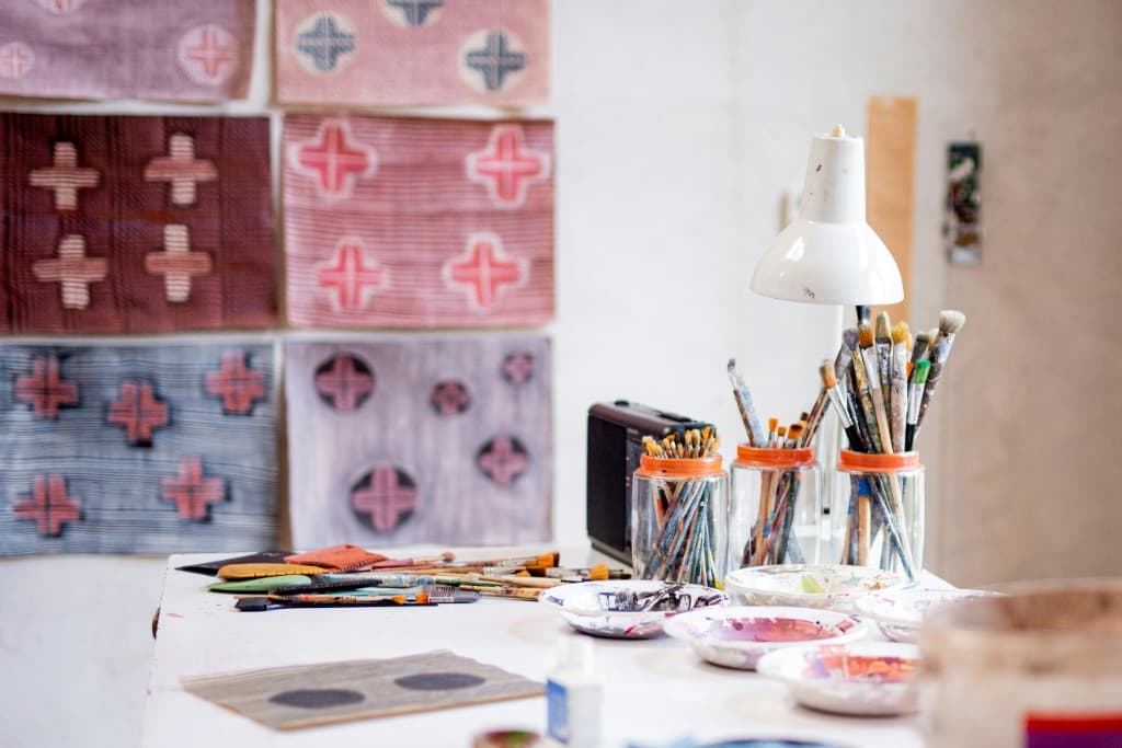 Artist studio with paintbrushes in jars and artwork on the wall
